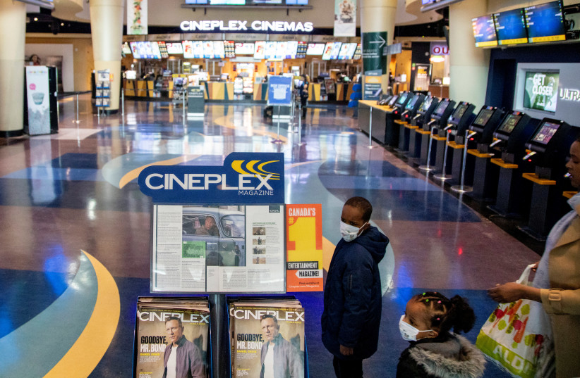 Two children and a woman enter a Cineplex Cinema as the number of novel coronavirus cases continued to grow in Toronto, Ontario, Canada March 16, 2020. (photo credit: REUTERS/CARLOS OSORIO)