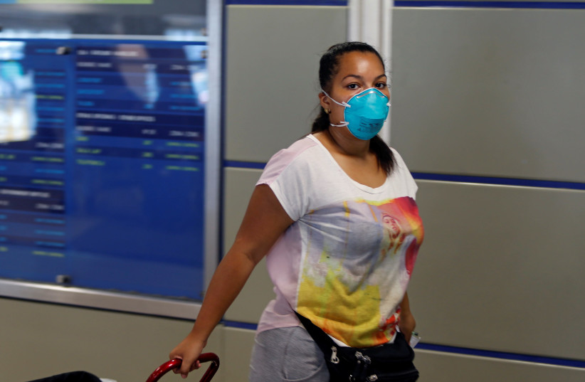 A woman wears a protective face masks after a case of coronavirus was confirmed in the country, at Jorge Chavez International Airport in Lima, Peru March 6, 2020. (photo credit: SEBASTIAN CASTANEDA/REUTERS)