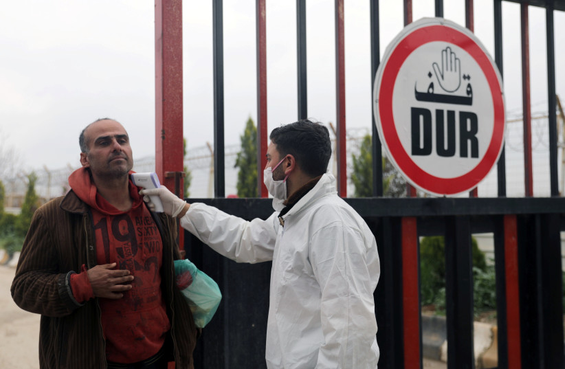 A health worker tests a man as part of security measures to avoid the spread of coronavirus, at the Bab el-Salam border crossing between the Syrian town of Azaz and the Turkish town of Kilis, seen from Syria (photo credit: REUTERS/KHALIL ASHAWI/FILE PHOTO)