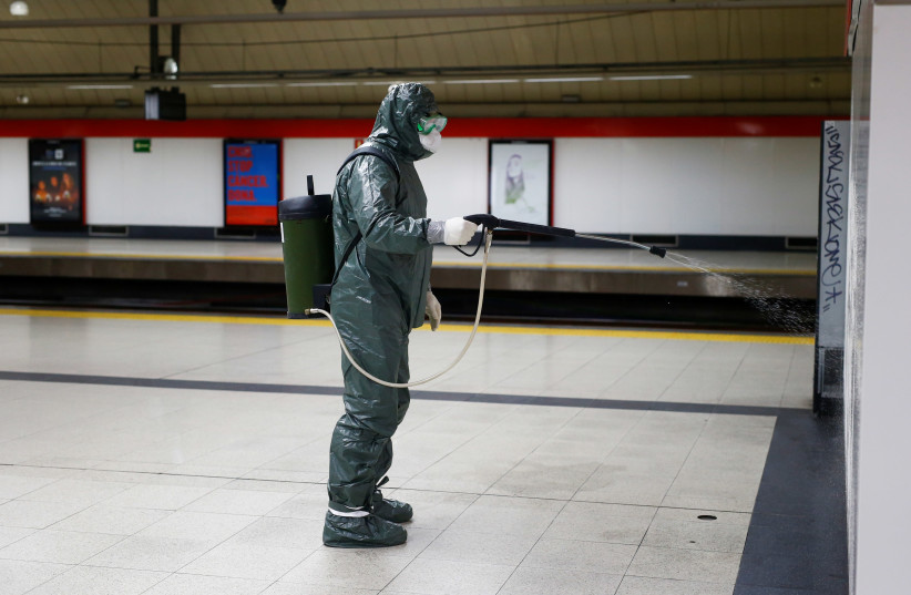 A Military Emergency Unit member disinfects a metro station due to coronavirus in Madrid, Spain. (photo credit: REUTERS/JAVIER BARBANCHO)