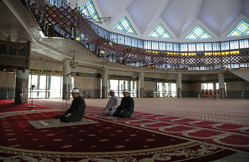 A Muslim Imam leads a prayer inside empty National Mosque, after all mosques in the country suspended Friday prayers during the movement control order due to the spread of the coronavirus disease (COVID-19), in Kuala Lumpur (photo credit: REUTERS)