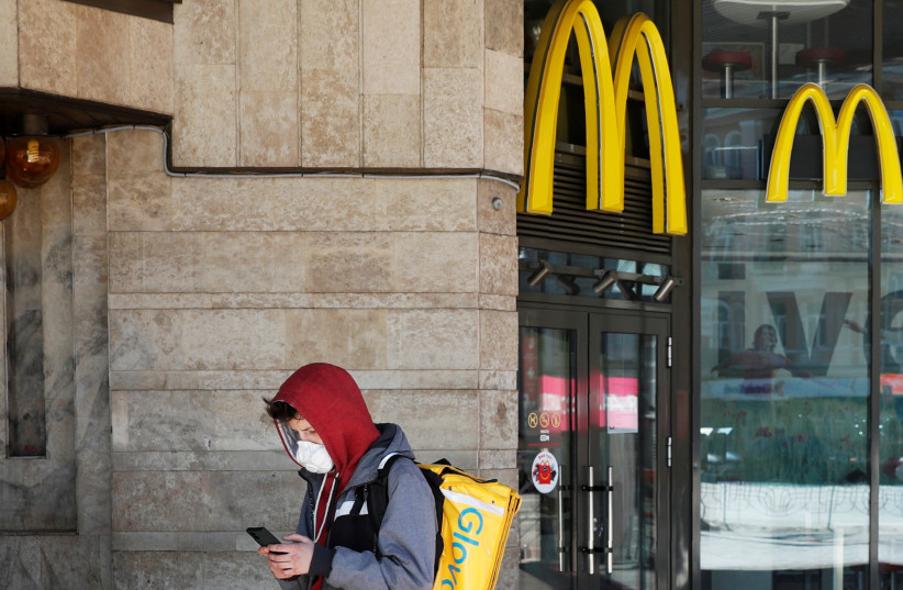 A Glovo food delivery courier wearing a protective mask checks an order outside a McDonald's restaurant in central Kiev (photo credit: REUTERS)
