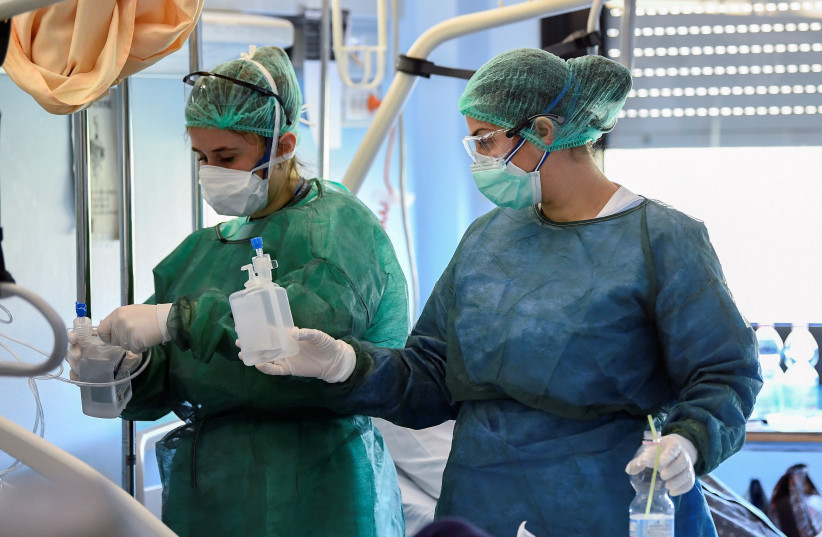 Medical staff wearing protective masks, glasses and suits treat a patient suffering from coronavirus disease (COVID-19) in an intensive care unit at the Oglio Po hospital in Cremona, Italy March 19, 2020 (photo credit: REUTERS/FLAVIO LO SCALZO)