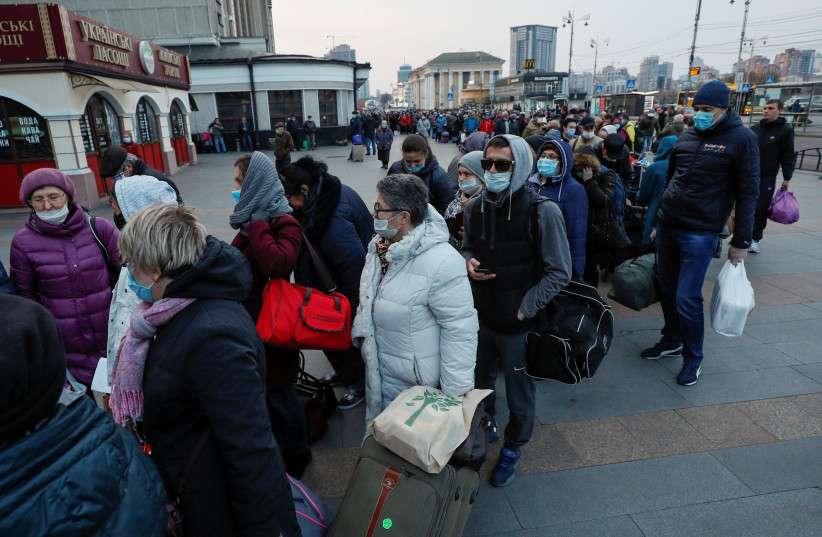 Passengers, including Russian citizens, who are evacuated by train to Russia after Ukrainian authorities shut the country's borders amid the spread of coronavirus disease (COVID-19), queue outside the Central Railway Station in Kiev, Ukraine March 27, 2020 (photo credit: REUTERS/GLEB GARANICH)