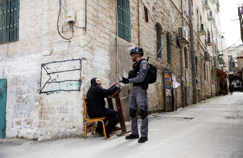 Un homme juif ultra-orthodoxe parle à un policier israélien après que la police l'ait sorti d'une synagogue avant de la fermer, car ils imposent des restrictions de verrouillage partiel contre la maladie à coronavirus (COVID-19) dans le quartier Mea Shearim de Jérusalem le 30 mars 2020. ( crédit photo: RONEN ZVULUN / REUTERS)