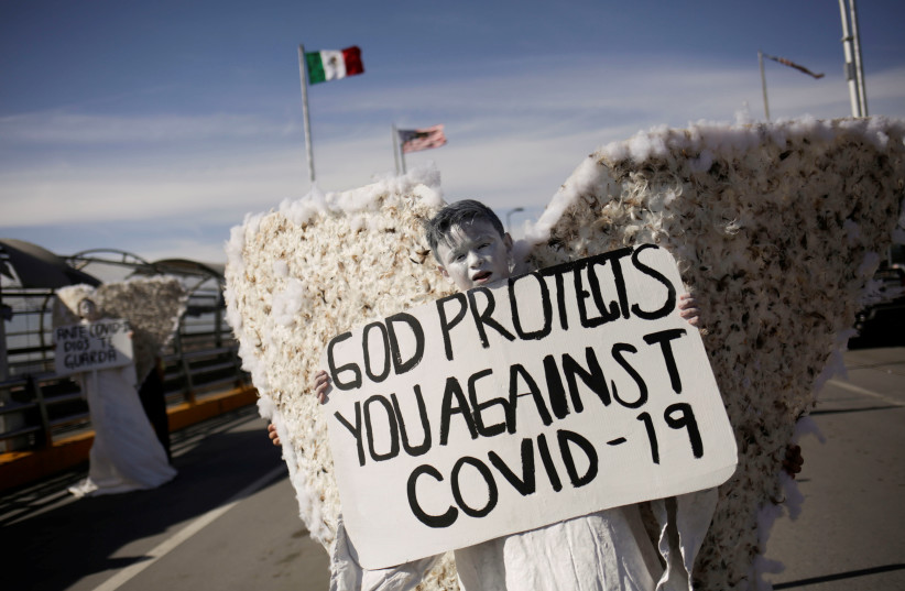 Members of the "Psalm 100" evangelical church, dressed as angels and holding placards making reference to the coronavirus (COVID-19) are seen during a demonstration at the Paso del Norte international border bridge as taken from Ciudad Juarez, Mexico, 23 March 2020 (photo credit: REUTERS/JOSE LUIS GONZALEZ)