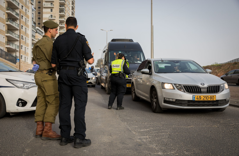 An Israeli police officer and an Israeli soldier at a temporary "checkpoint" in Jerusalem, to check people are not disobeying the governments orders on a partial lockdown, in order to prevent the spread of the Coronavirus on March 31, 2020. (photo credit: NATI SHOCHAT/FLASH 90)