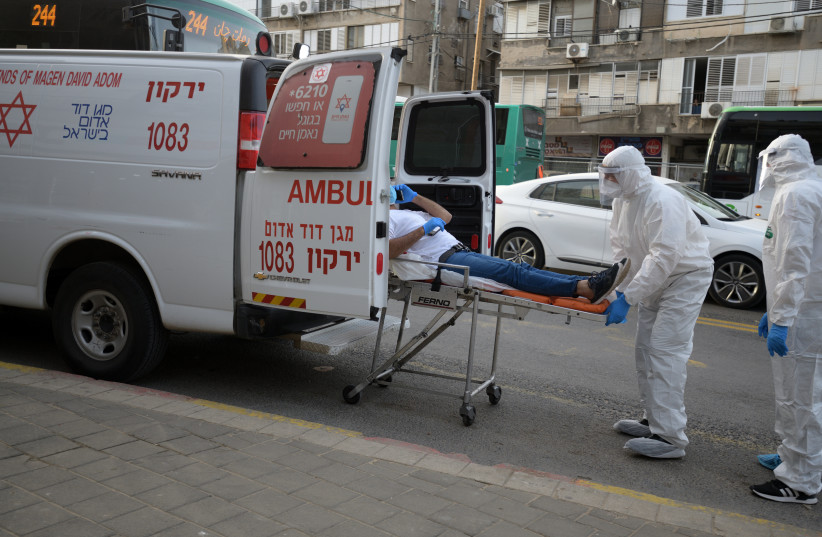 Israeli Magen David Adom medical team members transfer an Israeli man, suspected of being Covid-19 positive, in the Ultra-Orthodox Jewish city of Bnei Brak, March 31, 2020. (photo credit: GILI YAARI/FLASH90)