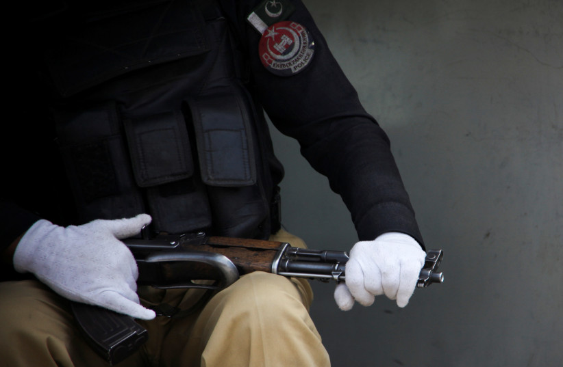 A police officer wears protective gloves, as a preventive measure against the coronavirus disease (COVID-19), while guarding outside railway station during a partial lockdown in Peshawar, Pakistan March 25, 2020 (photo credit: REUTERS/KHURRAM PARVEZ)