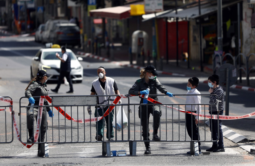 Israeli border policewomen chat with local residents at the entrance to Bnei Brak as Israel enforces a lockdown of the ultra-Orthodox Jewish town badly affected by coronavirus disease (COVID-19), Bnei Brak, Israel April 3, 2020 (photo credit: AMMAR AWAD / REUTERS)