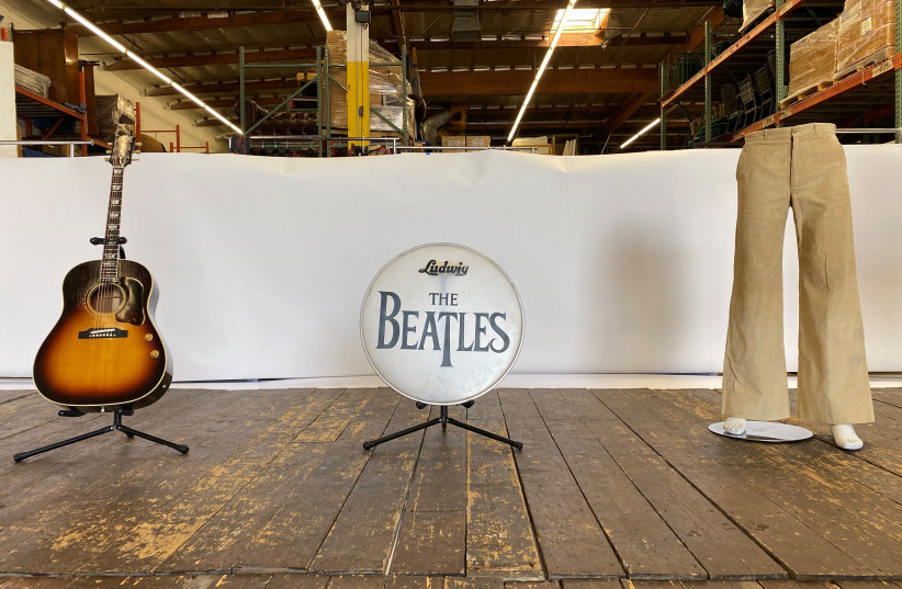 A wooden stage from the Liverpool venue where the Beatles performed before they became famous, with a pair of pants worn by John Lennon, a guitar played by Paul McCartney and a bass drumhead printed with The Beatles' logo (photo credit: REUTERS/JANE ROSS)