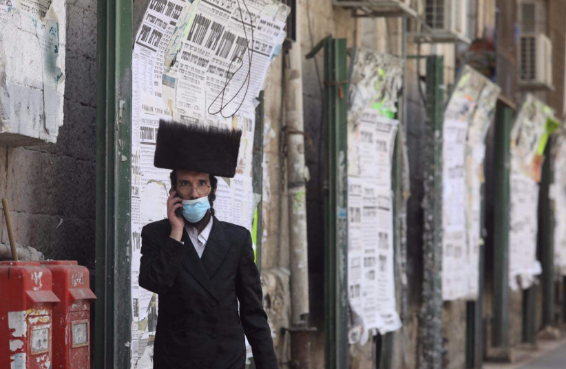 An ultra-Orthodox man wearing a mask walks around the neighborhood of Mea Shearim, Jerusalem, April 12, 2020 (photo credit: MARC ISRAEL SELLEM/THE JERUSALEM POST)