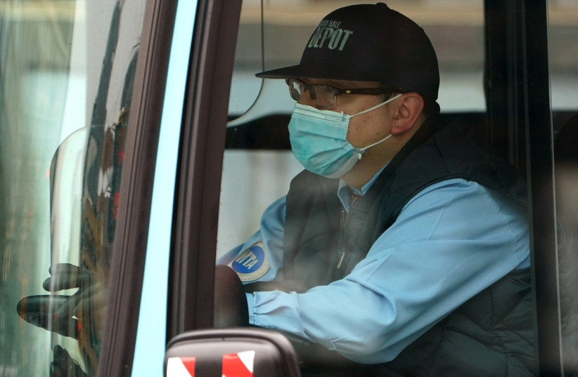 A bus driver wears a mask following the outbreak of coronavirus disease (COVID-19), in the Manhattan borough of New York City, New York, U.S., March 20, 2020. (photo credit: REUTERS/CARLO ALLEGRI)