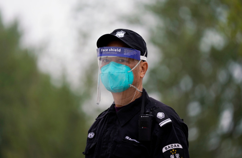 Security guard wearing face mask and face shield is seen in Wuhan (photo credit: REUTERS)