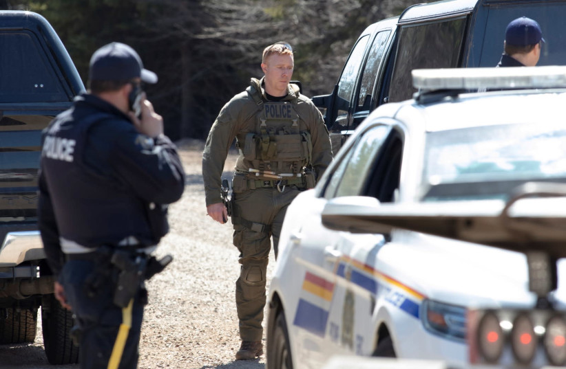 RCMP officers stand on Portapique Beach Road after Gabriel Wortman, a suspected shooter, was taken into custody and was later reported deceased according to local media, in Portapique, Nova Scotia, Canada April 19, 2020 (photo credit: REUTERS)