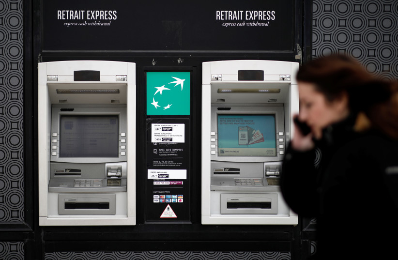 A woman passes in front of an ATM cash machine of the BNP Paribas bank at the financial and business district of La Defense near Paris, France, February 4, 2020. (photo credit: REUTERS/BENOIT TESSIER)