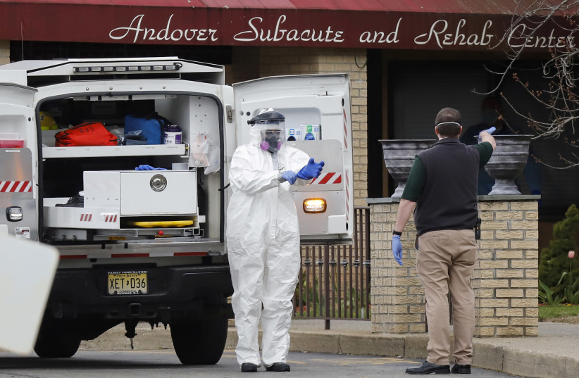 Paramedics and healthcare officials are seen outside Andover Subacute and Rehab Center, during the coronavirus disease (COVID-19) outbreak, in Andover, New Jersey, U.S., April 16, 2020. (photo credit: REUTERS/STEFAN JEREMIAH)