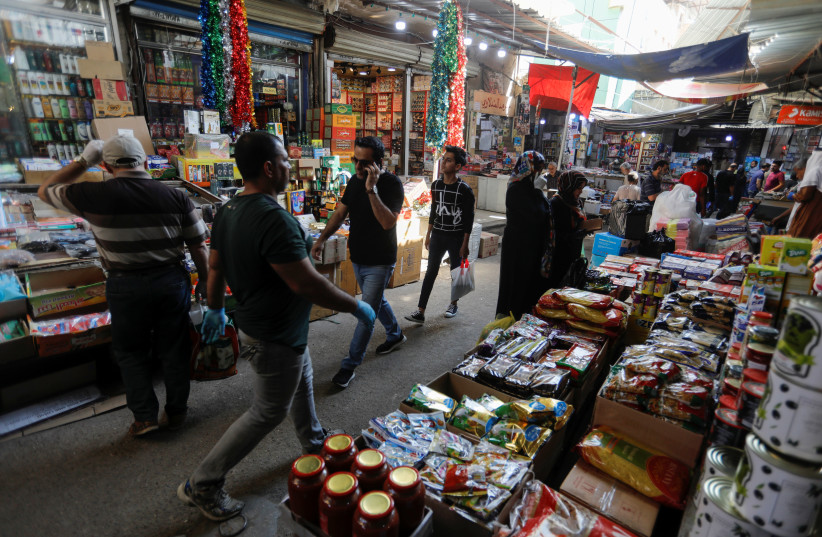 People shop after the lockdown measures, following the outbreak of the coronavirus disease (COVID-19), were partially eased, to prepare for the holy month of Ramadan, in Baghdad, Iraq, April 21, 2020. (photo credit: KHALID AL MOUSILY / REUTERS)