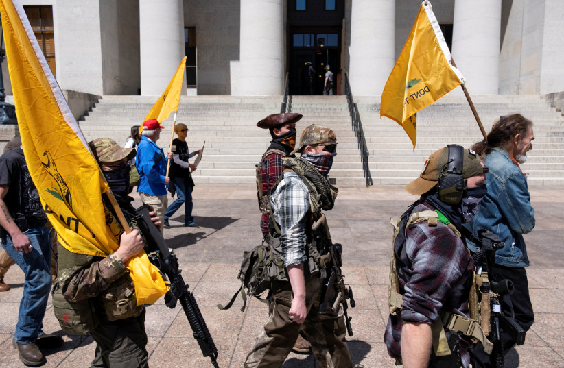 A militia group from Ohio protests against the state's extended stay-at-home order to help slow the spread of the Coronavirus disease (COVID-19) demonstrate at the Capitol building in Columbus, Ohio, U.S. April 20, 2020. (photo credit: REUTERS/SETH HERALD)