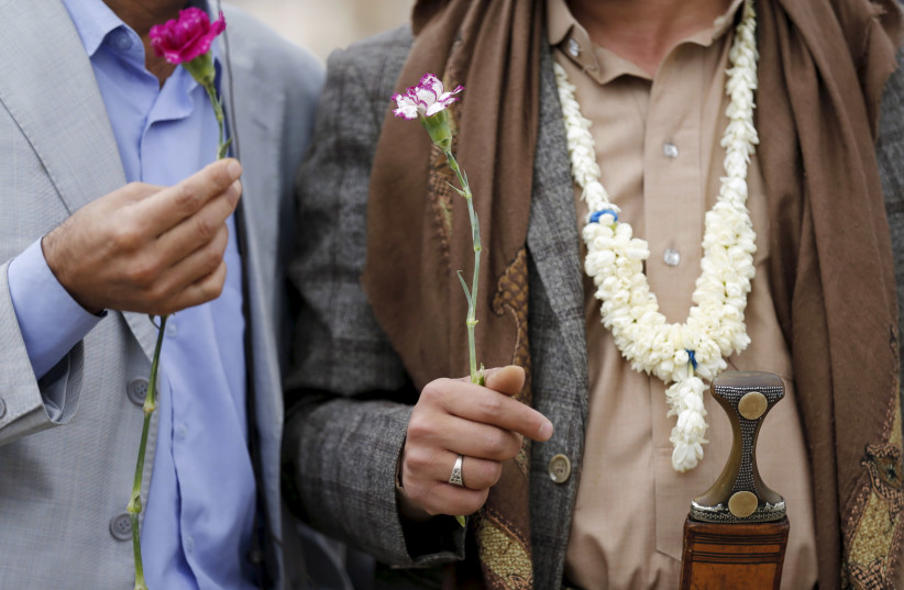 Members of the Baha'i faith hold flowers as they demonstrate outside a state security court during a hearing in the case of a fellow Baha'i man charged with seeking to establish a base for the community in Yemen, in the country's capital Sanaa April 3, 2016 (credit: REUTERS/KHALED ABDULLAH)