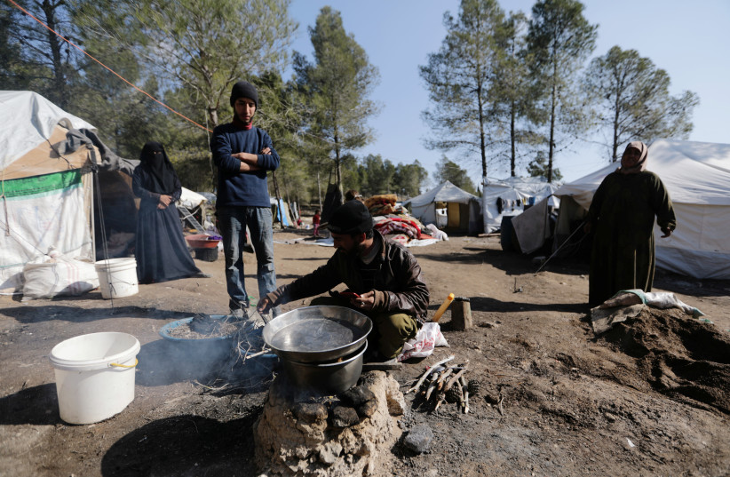 Aziza Hadaja, an internally displaced woman, stands with others outside tents near the town of Afrin, Syria February 17, 2020. Picture taken February 17, 2020 (photo credit: KHALIL ASHAWI / REUTERS)