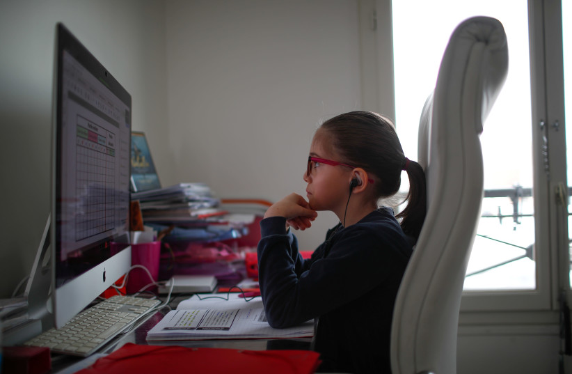 Anais, a student at the International Bilingual School (EIB), attends her online lessons in her bedroom in Paris as a lockdown is imposed to slow the rate of the coronavirus disease (COVID-19) spread in France, March 20, 2020. (credit: REUTERS/GONZALO FUENTES/FILE PHOTO)