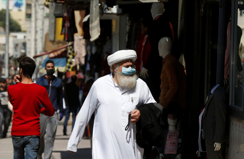 A man wears a protective face mask as he walks along the main market in downtown after the government eased the restrictions on movement aimed at containing the spread of the coronavirus in Amman, Jordan (photo credit: MUHAMMAD HAMED/REUTERS)