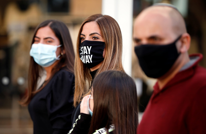 Shoppers wear face masks and walk around a fashion shopping center in Ashdod, as restrictions over the coronavirus disease (COVID-19) ease around Israel, May 5, 2020.  (photo credit: AMIR COHEN/REUTERS)