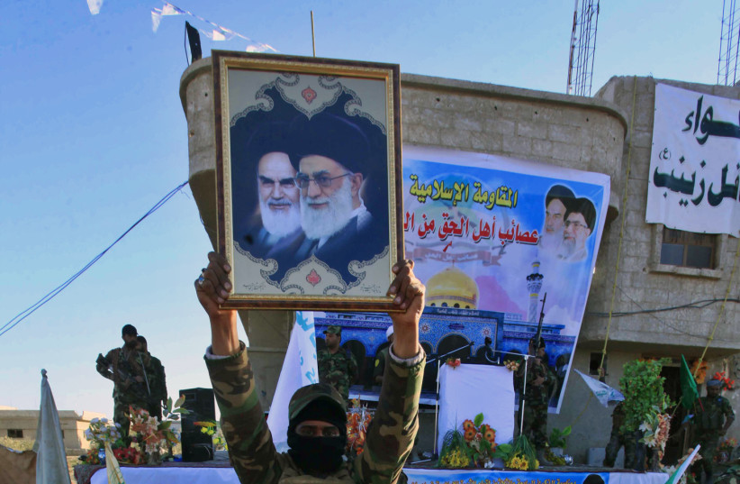 An Iraqi Shi'ite fighter holds a picture of Iran's Supreme Leader Ayatollah Ali Khamenei and cleric Ayatollah Khomeini during a military-style training at a camp on the outskirt of Damascus (photo credit: ALAA AL-MARJANI/REUTERS)