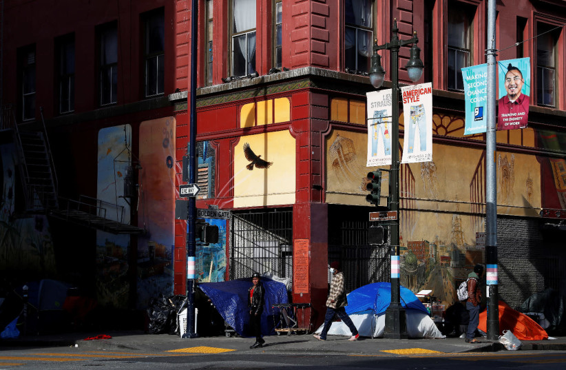 Tents set up by homeless people are seen on a corner street as people walk by amid an outbreak of the coronavirus disease (COVID-19), in the Tenderloin district of San Francisco, California, U.S. March 27, 2020 (credit: REUTERS)