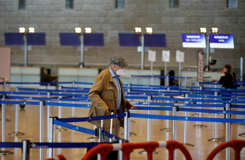 A man wearing a mask walks in the departures terminal after Israel said it will require anyone arriving from overseas to self-quarantine for 14 days as a precaution against the spread of coronavirus, at Ben Gurion International airport in Lod, near Tel Aviv, Israel March 10, 2020.  (photo credit: RONEN ZVULUN / REUTERS)
