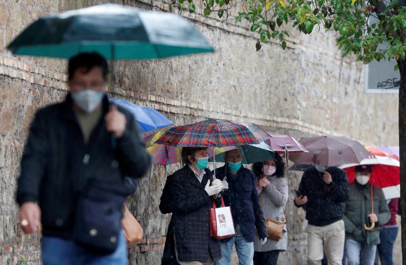 ILE PHOTO: People queue to receive free protective masks that have been bought by evangelicals in China and are distributed by Members of the Evangelical Christian Church, as the spread of the coronavirus disease (COVID-19) continues, in Rome, April 22, 2020 (credit: REUTERS/YARA NARDII/FILE PHOTO)