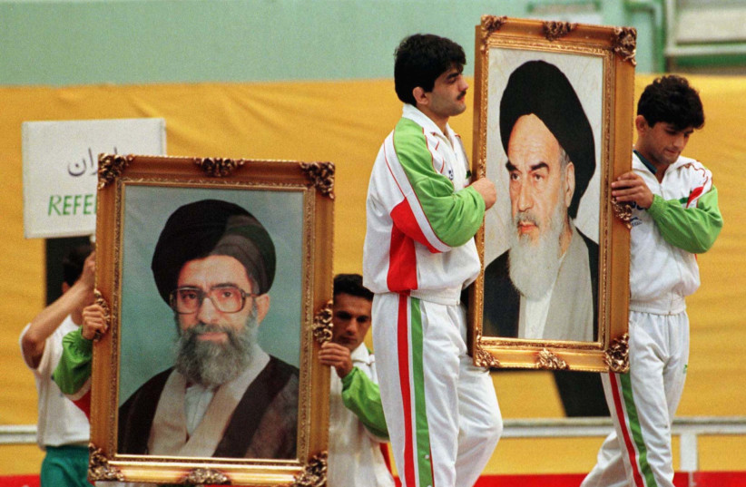Iranian wrestlers carry portraits of Iran’s late leader Ayatollah Ruhollah Khomeini and today’s