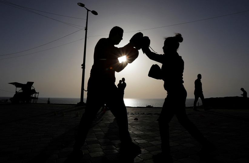 A Palestinian boxing coach, Osama Ayob, trains a girl at the sidewalk of a beach as sports clubs are closed due to concerns about the spread of the coronavirus disease (COVID-19), in Gaza City May 21, 2020. (photo credit: SUHAIB SALEM/REUTERS)