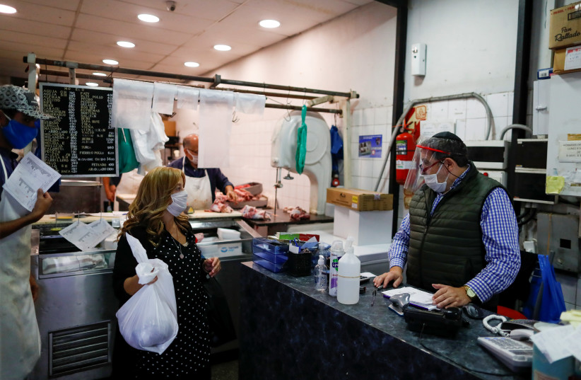 A BUTCHER SPEAKS with a customer at his kosher butcher shop in Buenos Aires, as Argentina works to organize the arrival of rabbis from Israel to keep kosher beef supply lines going in the midst of coronavirus restrictions on Wednesday (credit: REUTERS/AGUSTIN MARCARIAN)