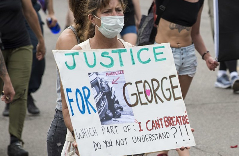 On May 26, 2020, people protested against police violence after the death of George Floyd. Focus on one protester with a "Justice for George" sign. (photo credit: Wikimedia Commons)