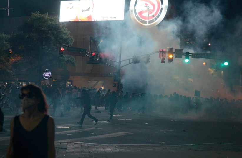 Protesters flee tear gas during a protest against the death in Minneapolis police custody of African-American man George Floyd, in Atlanta, Georgia, U.S. May 29, 2020. (photo credit: REUTERS/DUSTIN CHAMBERS)