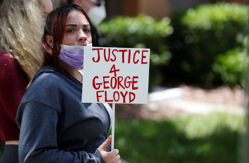 A protester holds a sign outside the Florida home of former Minneapolis police officer Derek Chauvin, in Orlando (photo credit: REUTERS)