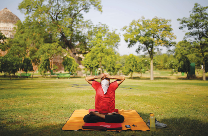 A MAN wearing a protective face covering performs a yoga exercise inside a park after some restrictions were lifted this week, during an extended nationwide lockdown to slow the spread of coronavirus in New Delhi, India. (credit: REUTERS)