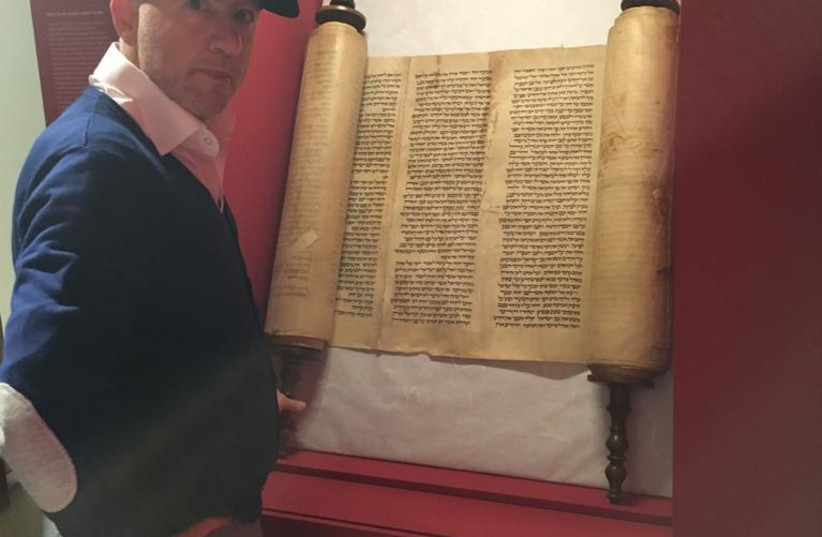 Rabbi Amedeo Spagnoletto with 13th century Torah scroll  (credit: MARCO CASELLI / MUSEUM OF ITALIAN JUDAISM AND THE HOLOCAUST)