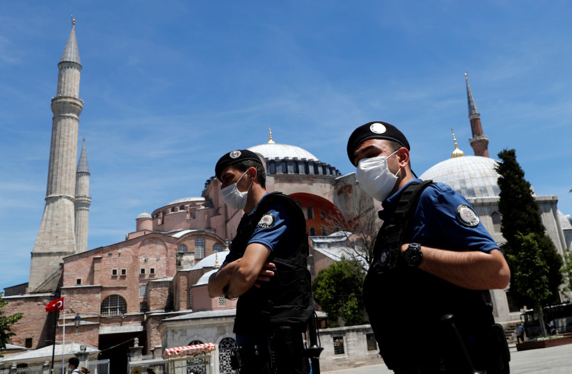 Des policiers turcs portant des masques faciaux, avec le monument de l'époque byzantine de Sainte-Sophie, maintenant un musée, en arrière-plan, patrouillent sur la place touristique Sultanahmet à la suite de l'épidémie de maladie à coronavirus (COVID-19), à Istanbul, Turquie, le 5 juin 2020 (crédit : REUTERS/MURAD SEZER)