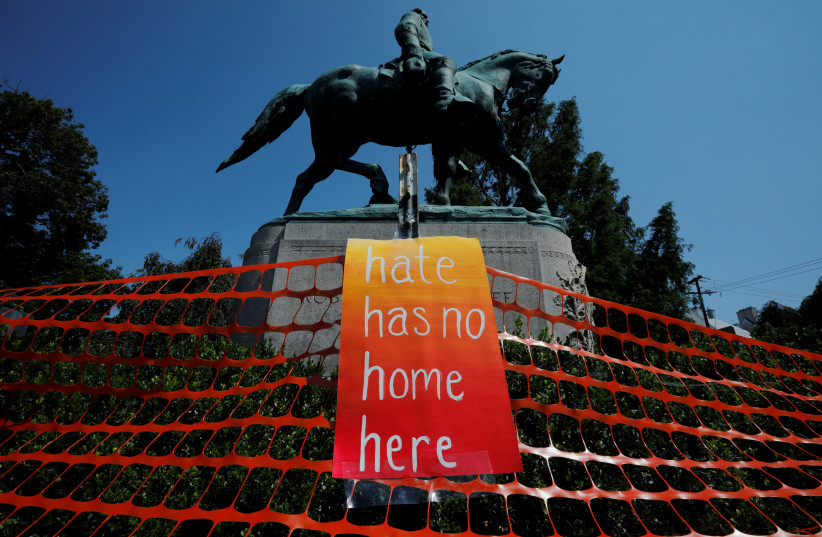 A sign reading "Hate Has No Home Here" hangs by the statue of Civil War Confederate General Robert E. Lee, ahead of the one year anniversary of 2017 Charlottesville "Unite the Right" protests, in Charlottesville, Virginia, U.S., August 10, 2018 (photo credit: BRIAN SNYDER/REUTERS)