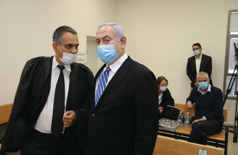 Prime Minister Benjamin Netanyahu, wearing a mask, stands inside the courtroom as his corruption trial opens at the Jerusalem District Court May 24, 2020. (photo credit: REUTERS/RONEN ZEVULUN)