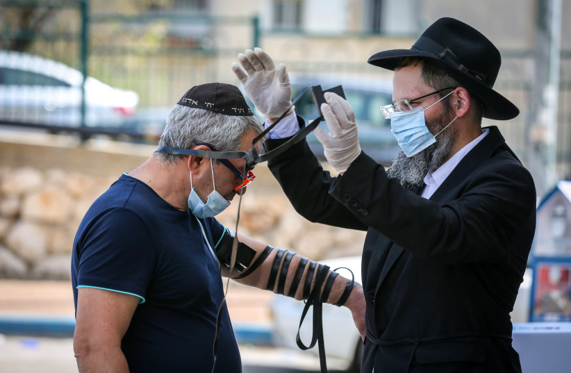 A CHABADNIK helps a man put on tefillin in Safed. (photo credit: DAVID COHEN/FLASH 90)