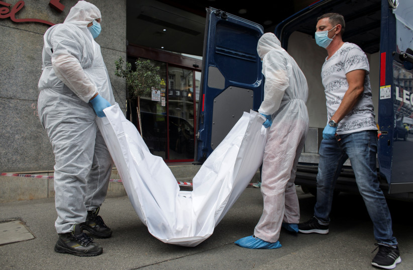 Forensic medicine staff carry a body bag, allegedly containing the remains of Gholamreza Mansouri, outside a hotel in downtown Bucharest, Romania, June 19, 2020. (photo credit: REUTERS)