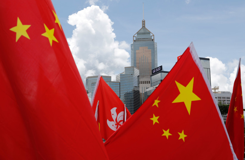 Buildings are seen above Hong Kong and Chinese flags, as pro-China supporters celebration after China's parliament passes national security law for Hong Kong, in Hong Kong, China June 30, 2020. (photo credit: REUTERS)