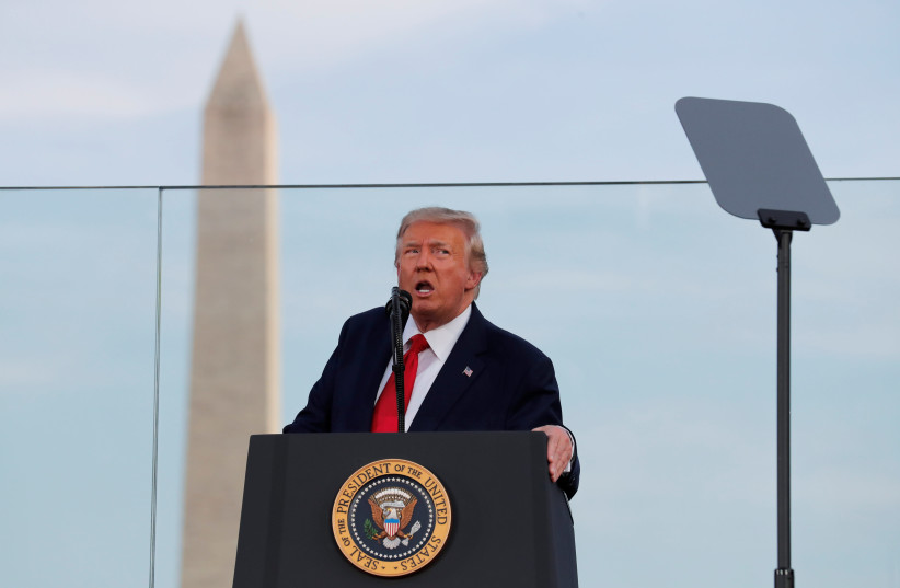 US President Donald Trump speaks to attendees with a sheet of bullet proof glass and the Washington Monument in the background as he hosts a 4th of July "2020 Salute to America" to celebrate the US Independence Day holiday at the White House in Washington, US, July 4, 2020. (photo credit: CARLOS BARRIA / REUTERS)