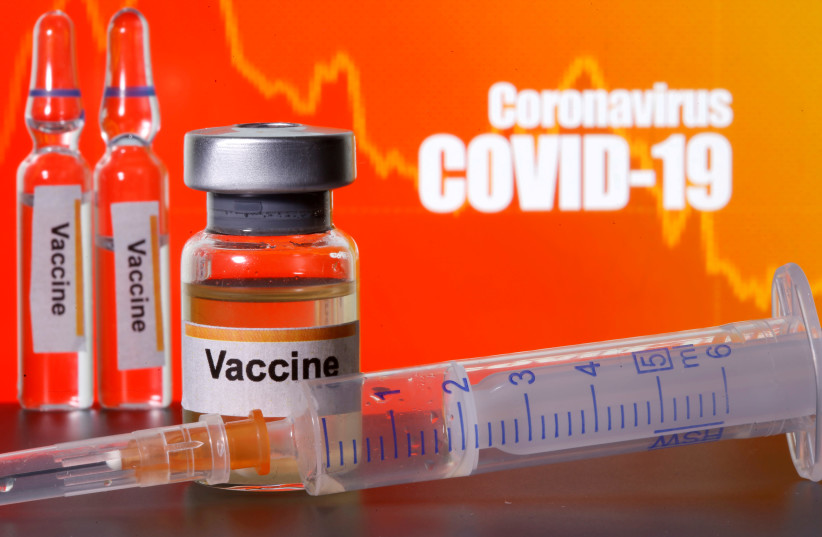 Bottles labeled "Vaccine" stand near medical syringe in front of "Coronavirus COVID-19" display (illustrative) (photo credit: REUTERS/DADO RUVIC/ILLUSTRATION/FILE PHOTO)