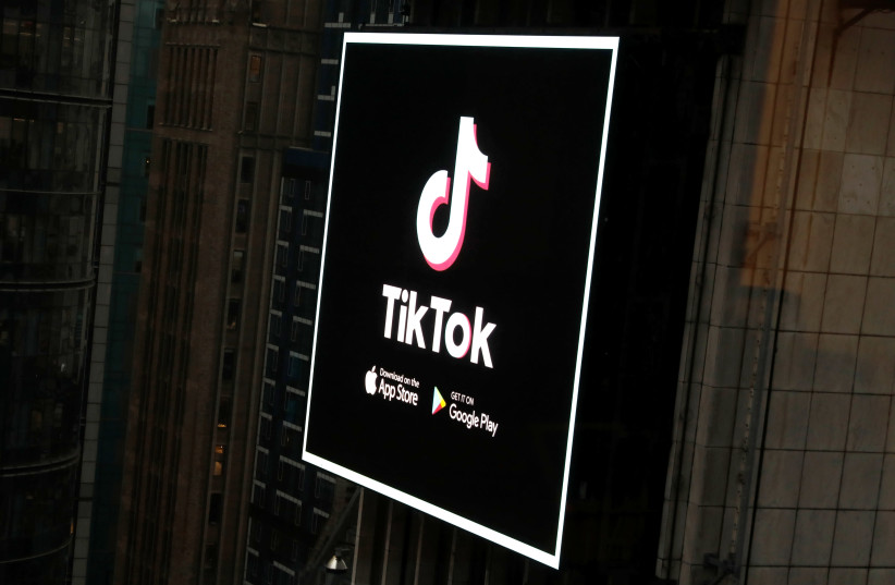 The TikTok logo is seen on a screen over Times Square in New York City, U.S., March 6, 2020 (photo credit: REUTERS/ANDREW KELLY)