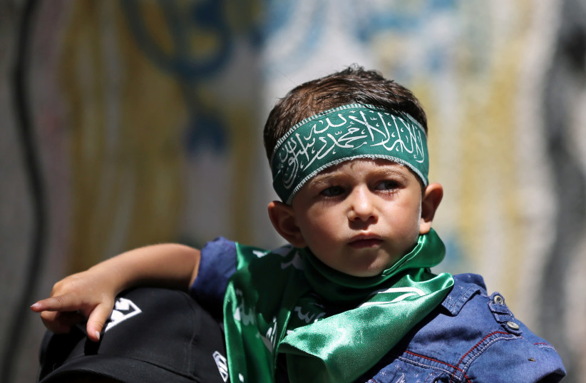 A Palestinian boy wearing a Hamas headband attends a protest against Israel's plan to annex parts of the occupied West Bank, in the southern Gaza Strip June 26, 2020 (photo credit: IBRAHEEM ABU MUSTAFA/REUTERS)